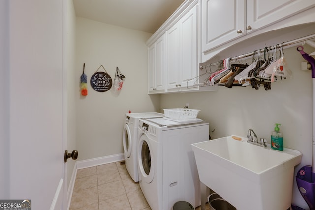 clothes washing area featuring washing machine and clothes dryer, cabinets, sink, and light tile patterned floors