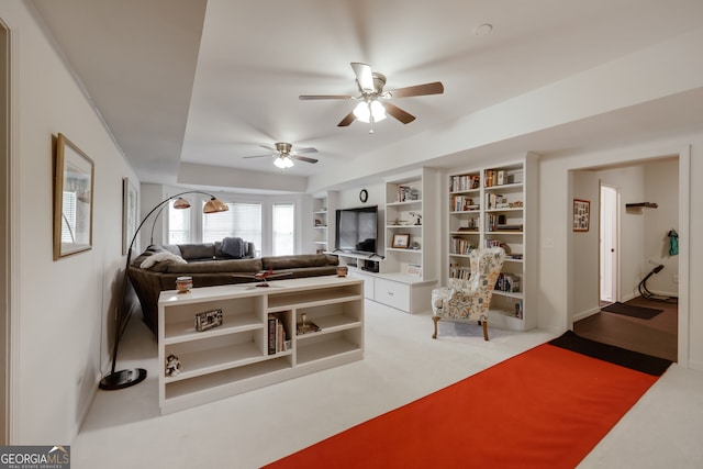 living room featuring built in shelves, ceiling fan, and light carpet