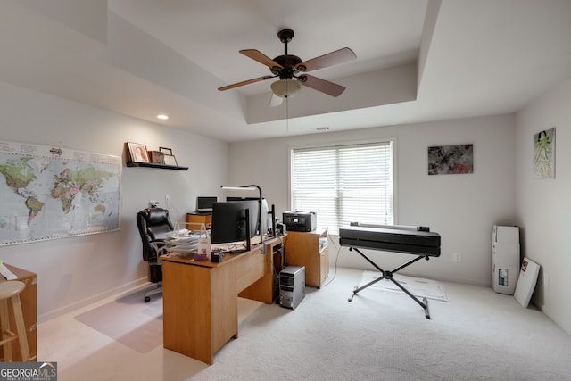 home office with ceiling fan, light colored carpet, and a raised ceiling