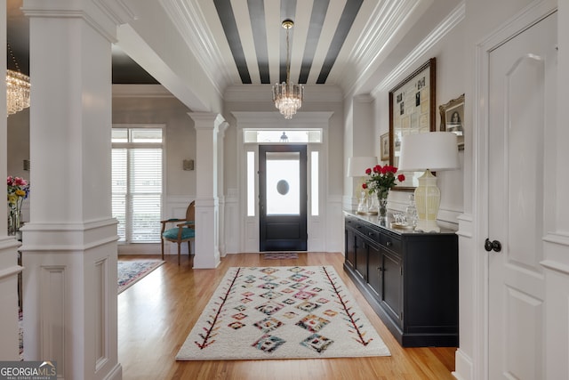 foyer with ornate columns, ornamental molding, a notable chandelier, and light hardwood / wood-style floors