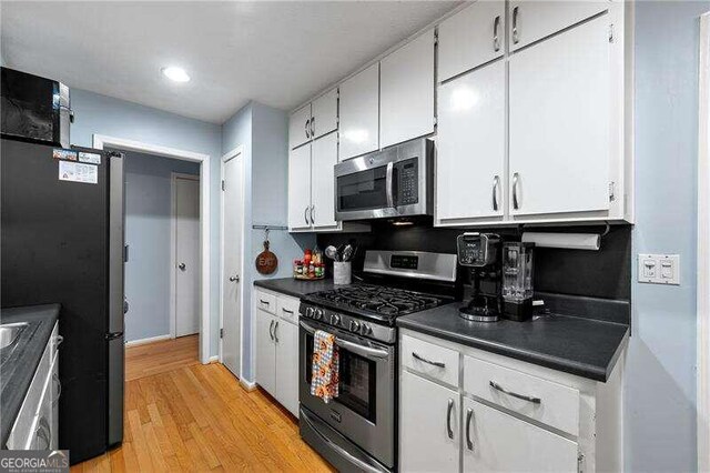 clothes washing area with attic access, light wood-type flooring, laundry area, and washer and clothes dryer