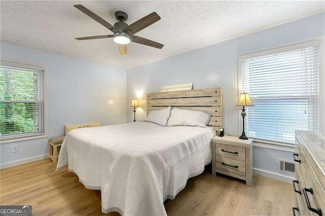 bedroom with a ceiling fan, baseboards, a textured ceiling, and light wood finished floors