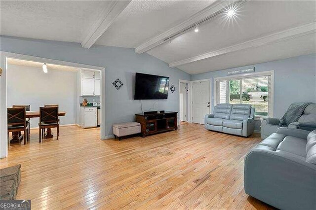 living room featuring baseboards, visible vents, wood finished floors, vaulted ceiling with beams, and a fireplace