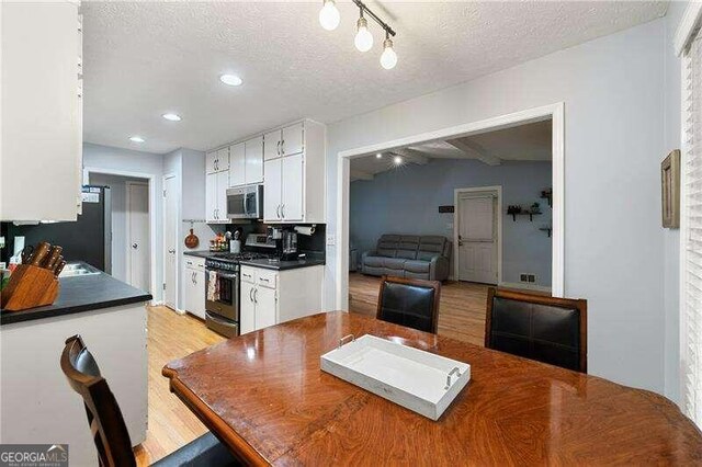 living room featuring lofted ceiling with beams, light wood finished floors, and baseboards