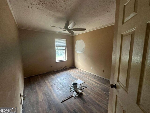 spare room featuring crown molding, dark wood-type flooring, a textured ceiling, and ceiling fan