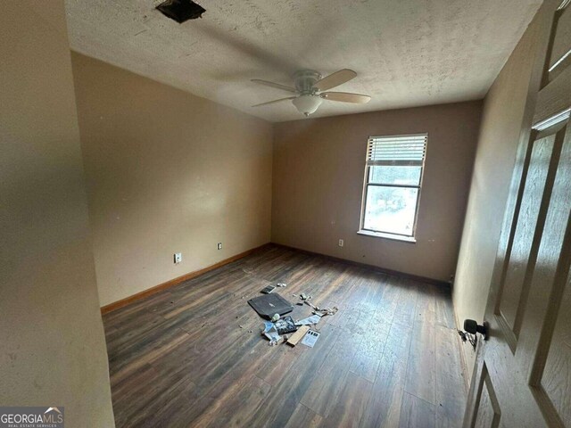 unfurnished room featuring ceiling fan, dark hardwood / wood-style flooring, and a textured ceiling