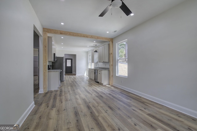 unfurnished living room featuring light wood-type flooring, ceiling fan, and sink