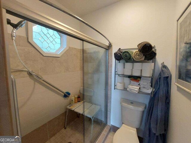 bathroom featuring toilet and an enclosed shower