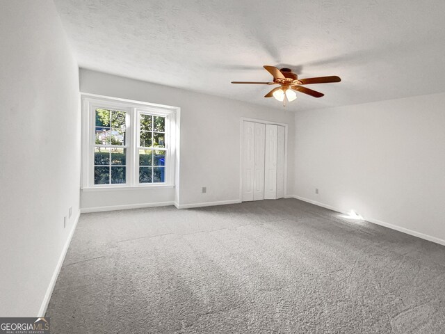 carpeted empty room with ceiling fan and a textured ceiling