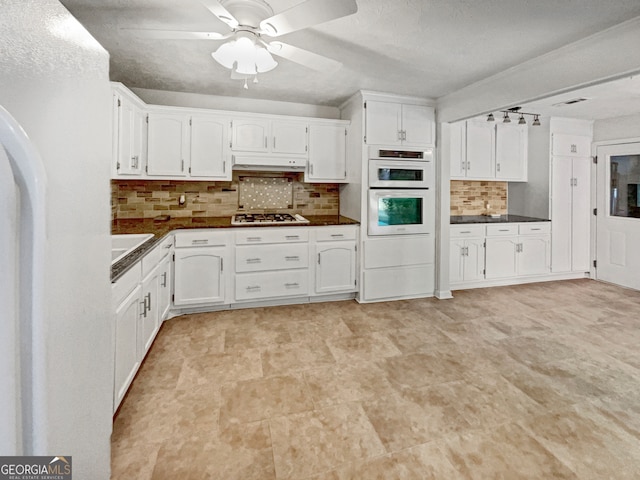 kitchen featuring stainless steel gas cooktop, white cabinetry, tasteful backsplash, white double oven, and ceiling fan