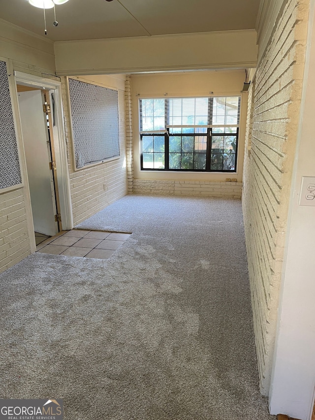 unfurnished living room with light carpet and brick wall