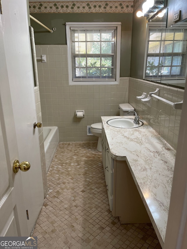 full bathroom with tile patterned flooring, toilet, tile walls, shower / bath combination, and vanity