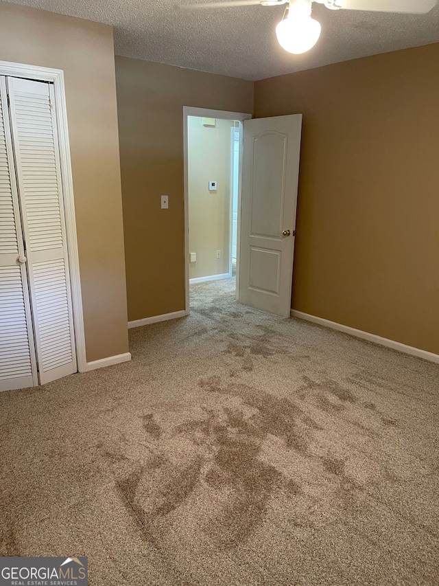 unfurnished bedroom featuring carpet flooring, a textured ceiling, and a closet