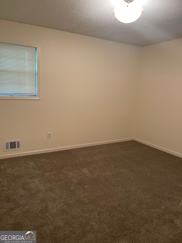 empty room featuring a textured ceiling and dark carpet