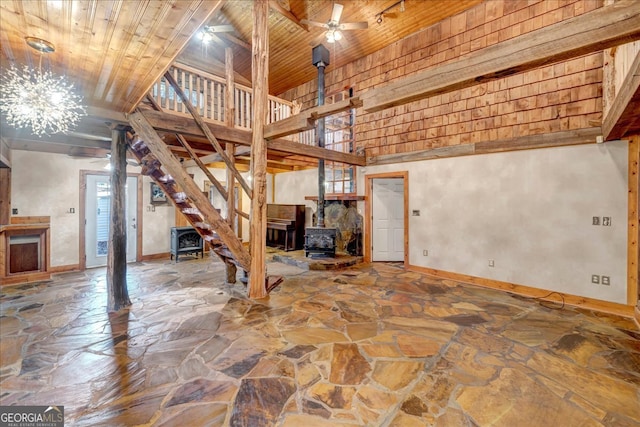 basement with ceiling fan with notable chandelier, a wood stove, and wooden ceiling