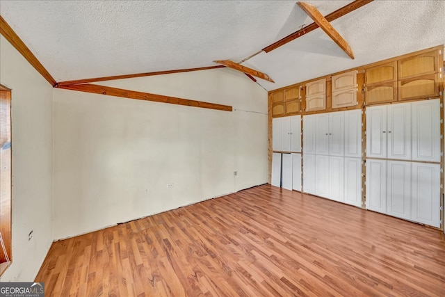 unfurnished bedroom with ornamental molding, a textured ceiling, light hardwood / wood-style flooring, and lofted ceiling