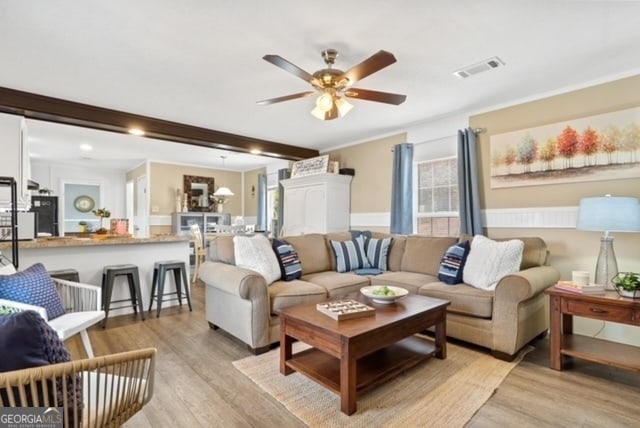 living room featuring ceiling fan, beamed ceiling, and light hardwood / wood-style floors