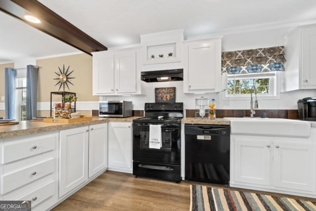 kitchen featuring white cabinets, black appliances, wood-type flooring, ornamental molding, and sink