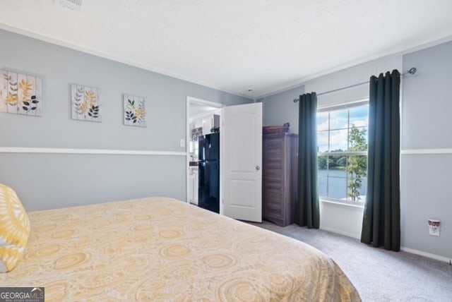 carpeted bedroom with black refrigerator