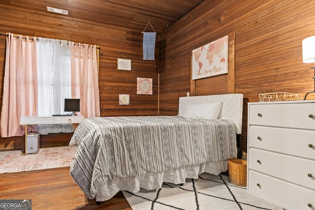 bedroom with wooden walls, wood ceiling, and light wood-type flooring