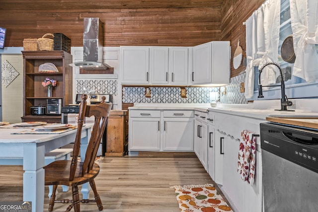 kitchen featuring white cabinets, backsplash, stainless steel dishwasher, light hardwood / wood-style floors, and wall chimney exhaust hood