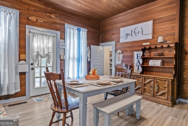 dining space with wood ceiling, light hardwood / wood-style flooring, and wood walls