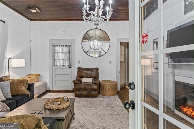 living room featuring an inviting chandelier, wooden walls, light hardwood / wood-style floors, and wooden ceiling