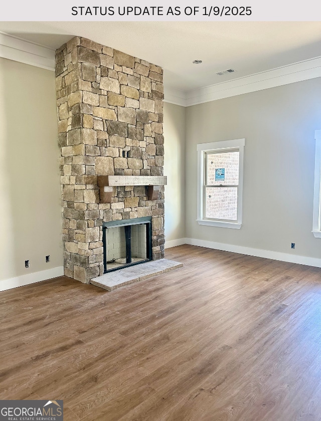 unfurnished living room featuring hardwood / wood-style floors, a stone fireplace, and crown molding