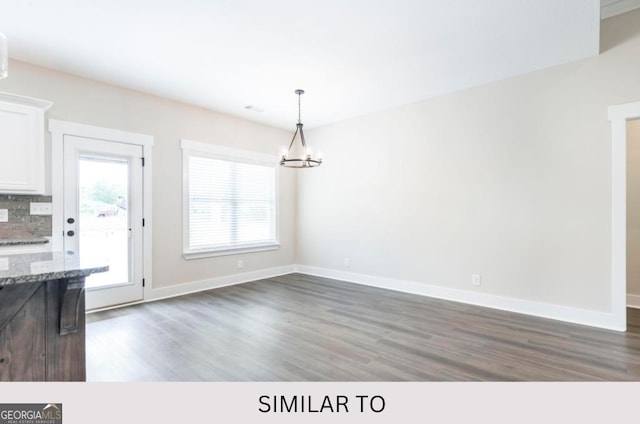 unfurnished dining area featuring dark hardwood / wood-style floors and a chandelier