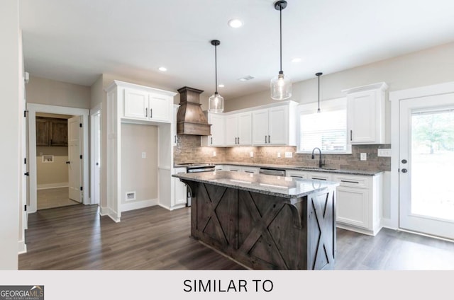 kitchen with white cabinetry, a center island, light stone counters, premium range hood, and decorative light fixtures