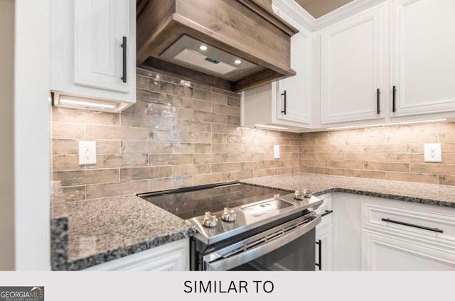 kitchen with tasteful backsplash, stone countertops, stainless steel electric stove, white cabinets, and custom range hood