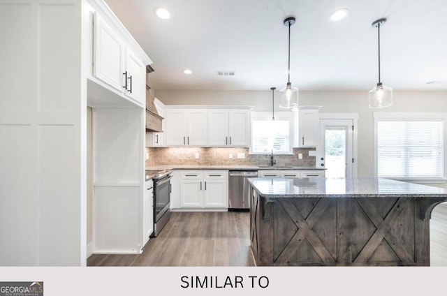 kitchen featuring sink, appliances with stainless steel finishes, decorative light fixtures, a kitchen island, and white cabinetry