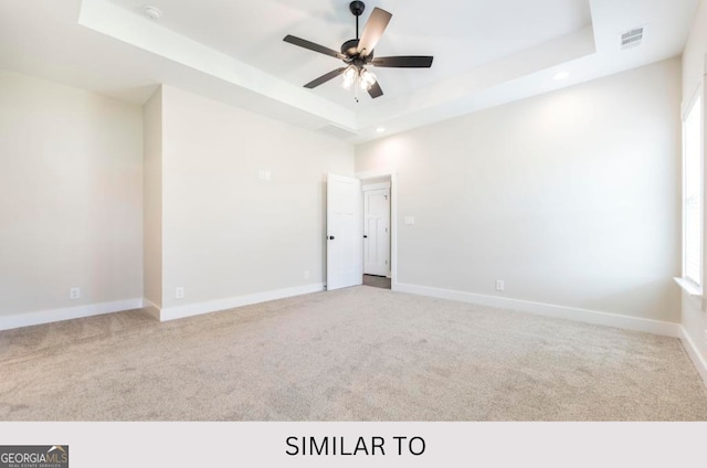 carpeted empty room featuring a tray ceiling and ceiling fan