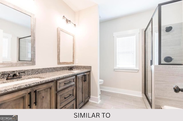 bathroom featuring vanity, toilet, and a shower with shower door