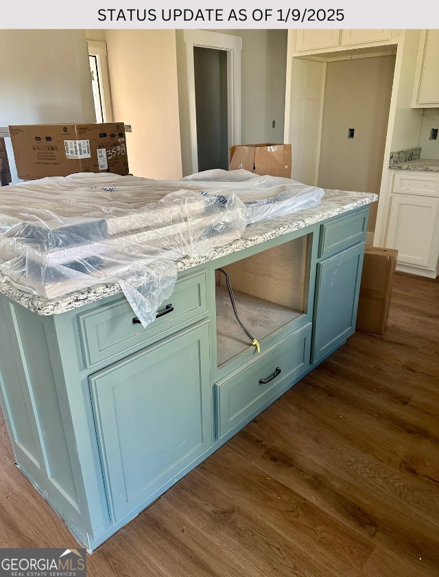 kitchen featuring light stone countertops, dark wood-type flooring, and green cabinetry