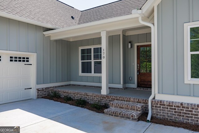170 New High Shoals Rd, Watkinsville, GA 30677 - doorway to property featuring board and batten siding, covered porch, roof with shingles, concrete driveway, and a garage