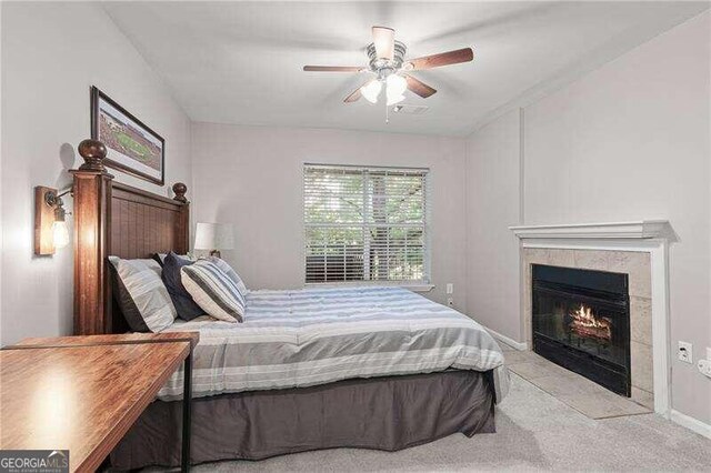 carpeted bedroom with ceiling fan and a tile fireplace