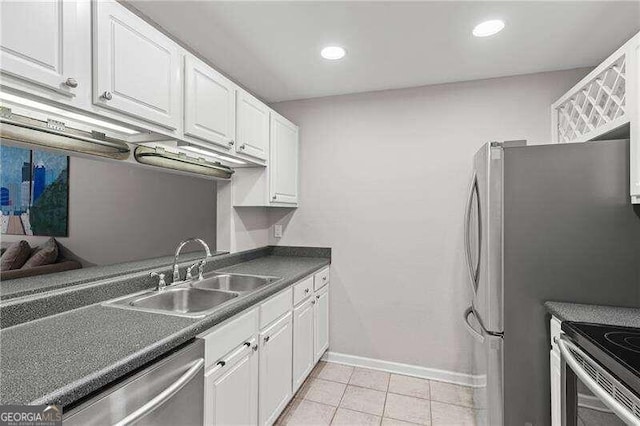 kitchen with dark countertops, white cabinetry, stainless steel appliances, and a sink