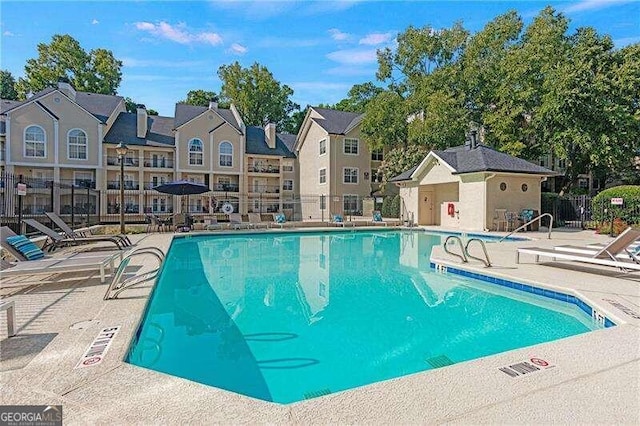 pool with a residential view, a patio, and fence