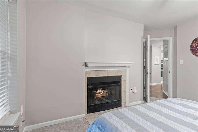 bedroom with light carpet and a tile fireplace