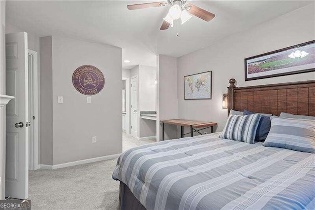 bedroom featuring light colored carpet, ensuite bath, baseboards, and ceiling fan