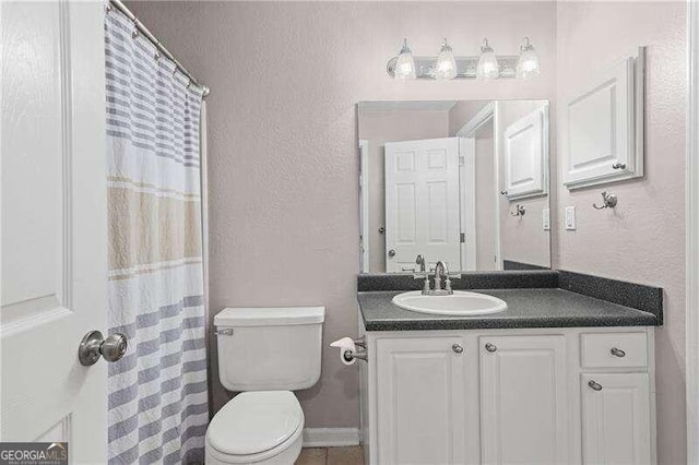 full bath featuring toilet, vanity, baseboards, and a textured wall