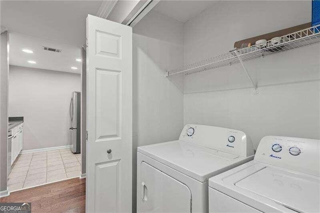 clothes washing area featuring washing machine and clothes dryer, visible vents, baseboards, light tile patterned floors, and laundry area