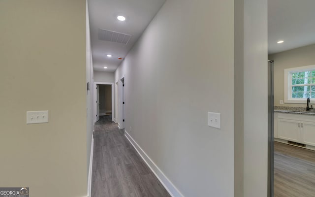 corridor featuring a sink, baseboards, visible vents, and wood finished floors