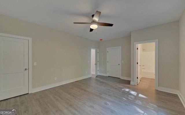 unfurnished bedroom with baseboards, wood finished floors, ceiling fan, and ensuite bathroom