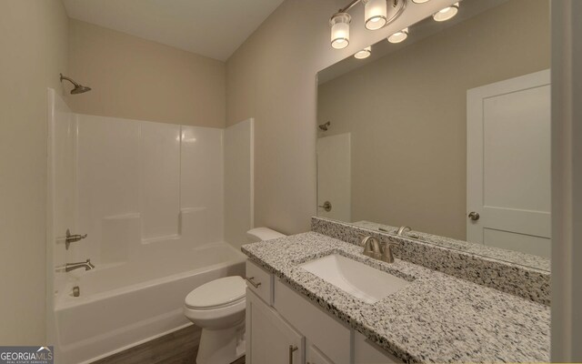 full bathroom featuring washtub / shower combination, wood-type flooring, toilet, and vanity