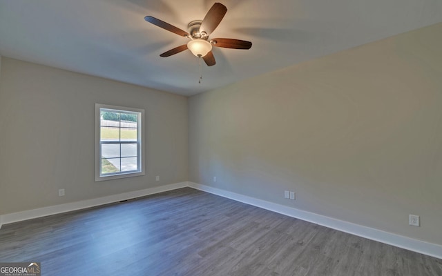 unfurnished room with baseboards, ceiling fan, and dark wood-style flooring