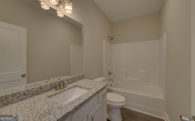 bathroom featuring toilet, vanity, tub / shower combination, and wood finished floors