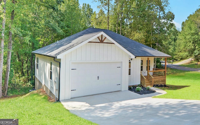 garage with a lawn and covered porch