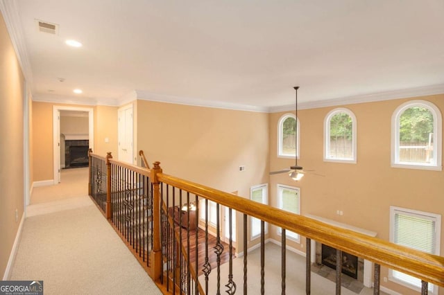 unfurnished living room featuring a fireplace, a raised ceiling, crown molding, and ceiling fan